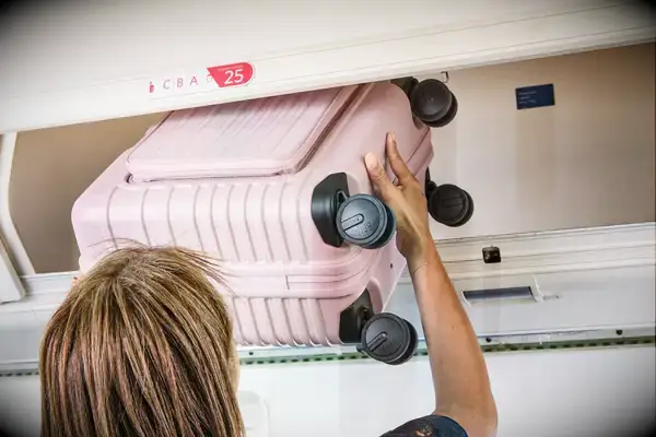 Someone putting the Beis Mini Roller in an overhead bin