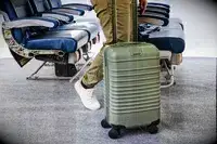 A person wheels the Béis The Small Carry-on Roller on carpet