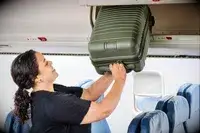 A person places the Béis The Small Carry-on Roller into an overhead compartment