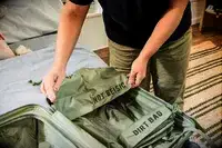 A person holds up additional bags that come with the Béis The Small Carry-on Roller