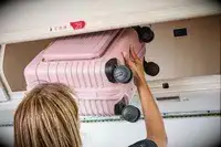 Someone putting the Beis Mini Roller in an overhead bin