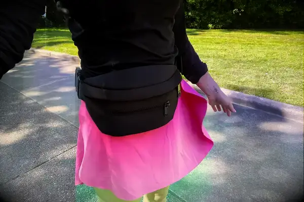 Person wearing Dagne Dover’s Ace Fanny Pack and a bright skirt walking outdoors