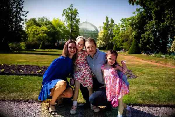 A family smiling in front of a garden in Paris