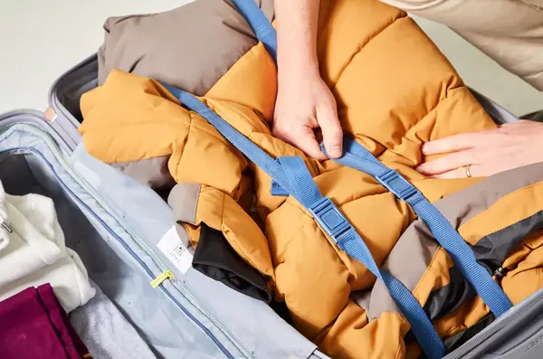 A hand touching the strap inside of a backed Delsey Paris Cruise 3.0 26 Inch Trunk