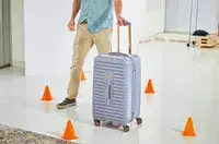 A person rolling the Delsey Paris Cruise 3.0 26 Inch Trunk through cones