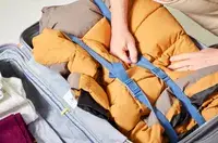 A hand touching the strap inside of a backed Delsey Paris Cruise 3.0 26 Inch Trunk