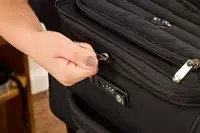 A person zips up the Delsey Paris Cruise 3.0 Soft Carry-On Expandable Spinner