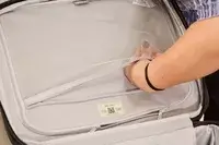 A person reaches inside the pocket of the Delsey Paris Cruise 3.0 Soft Carry-On Expandable Spinner