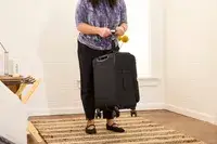 A person weighs the Delsey Paris Cruise 3.0 Soft Carry-On Expandable Spinner