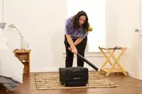 A person hits the Delsey Paris Cruise 3.0 Soft Carry-On Expandable Spinner with a baseball bat