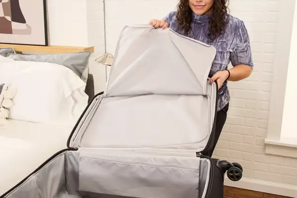 A person unzips the Delsey Paris Cruise 3.0 Soft Large Expandable Spinner