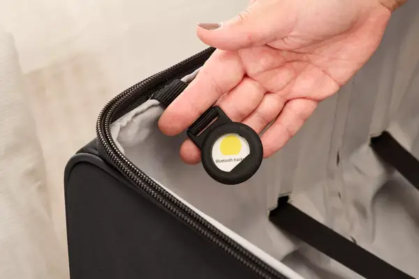 A person shows an Airtag holder attached to the inside of the Delsey Paris Cruise 3.0 Soft Large Expandable Spinner