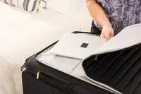 A person places a laptop into the Delsey Paris Cruise 3.0 Soft Large Expandable Spinner