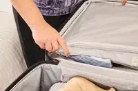 A person zips the Delsey Paris Cruise 3.0 Soft Large Expandable Spinner closed