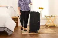 A person wheels the Delsey Paris Cruise 3.0 Soft Large Expandable Spinner over a rug