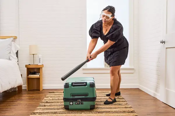 A person hits the Delsey X Jeep JH002B Large Expandable Spinner Trunk with a baseball bat