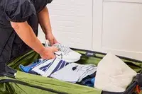 A person places shoes and clothing into the Delsey X Jeep JH002B Large Expandable Spinner Trunk