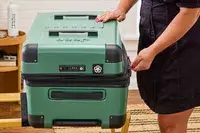 A person zips the Delsey X Jeep JH002B Large Expandable Spinner Trunk closed