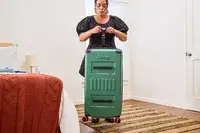 A person weighs the Delsey X Jeep JH002B Large Expandable Spinner Trunk