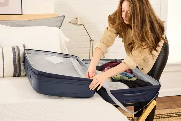 A person unzips a pocket on the Delsey Paris Dune Large Expandable Spinner