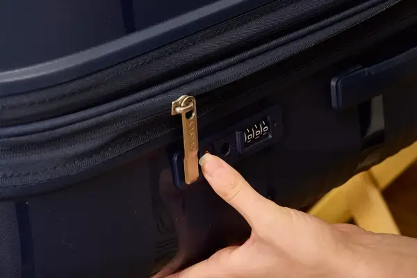 A person presses a lock on the Delsey Paris Dune Large Expandable Spinner