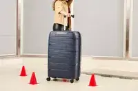 A person rolls the Delsey Paris Dune Large Expandable Spinner over a floor