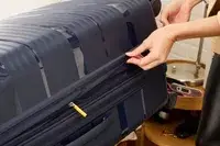 A person zips up the Delsey Paris Dune Large Expandable Spinner