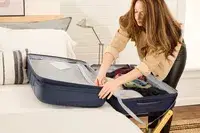 A person unzips a pocket on the Delsey Paris Dune Large Expandable Spinner