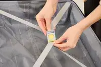 A person secures the strap on the Delsey Paris Dune Large Expandable Spinner