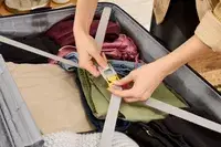 A person secures clothing in the Delsey Paris Dune Large Expandable Spinner