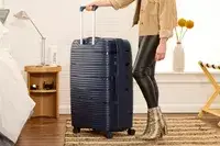 A person rolls the Delsey Paris Dune Large Expandable Spinner over a rug