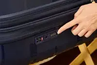 A person points to a lock on the Delsey Paris Dune Large Expandable Spinner