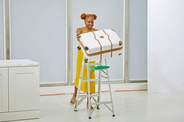 A person pushing the Delsey Paris Chatelet Air 2.0 24 Inch Checked Spinner off of a ladder