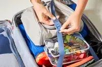 A person closing the clip to contain items in the Delsey Cruise 3.0 Carry-on - 21