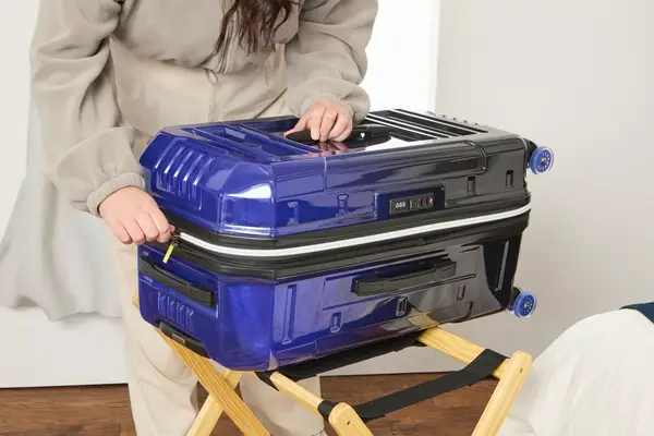 A person zips up the Delsey REMPART Medium Trunk Expandable Spinner