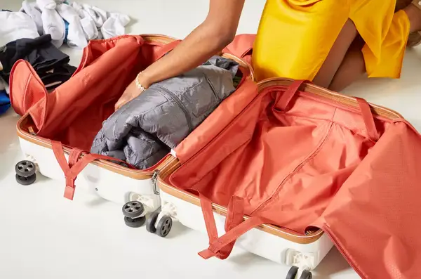 A hand adding an item into the Delsey Paris Chatelet Air 2.0 24 Inch Checked Spinner