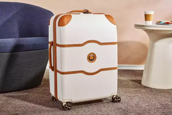 Delsey Paris Chatelet Air 2.0 24 Inch Checked Spinner on a carpet next to furniture