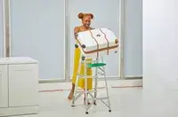 A person pushing the Delsey Paris Chatelet Air 2.0 24 Inch Checked Spinner off of a ladder