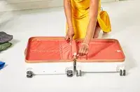 a person zippering a compartment inside of the Delsey Paris Chatelet Air 2.0 24 Inch Checked Spinner