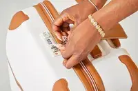 A person locking the Delsey Paris Chatelet Air 2.0 24 Inch Checked Spinner