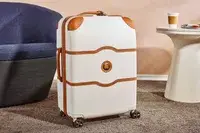 Delsey Paris Chatelet Air 2.0 24 Inch Checked Spinner on a carpet next to furniture