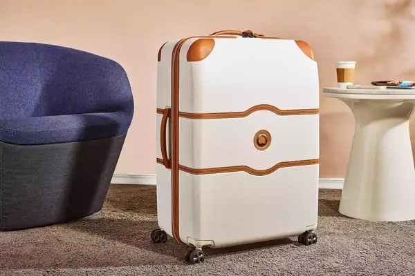 Delsey Paris Chatelet Air 2.0 28 Inch Large Checked Spinner on a carpet next to furniture