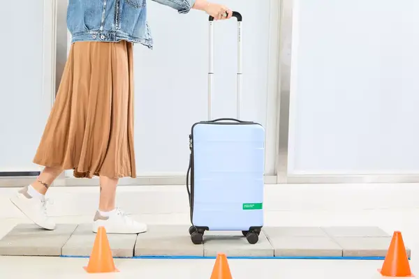 A person wheeling the DELSEY PARIS X United Colors of Bennetton Carry-on Spinner on tile