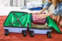 A person packing the DELSEY PARIS X United Colors of Bennetton Carry-on Spinner