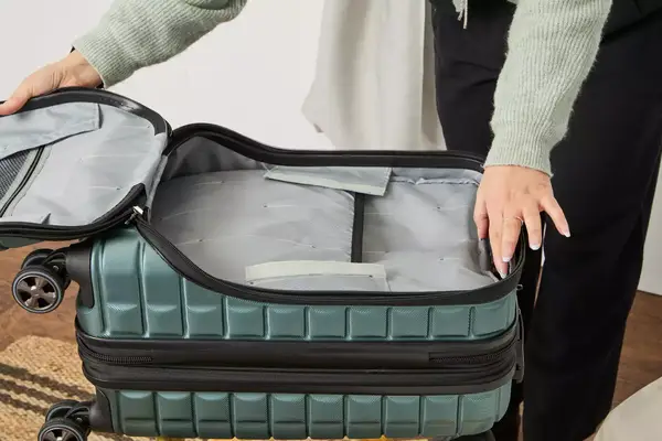 A person holds open the front pocket on the Delsey Paris Shadow 5.0 Carry-on with Laptop Compartment