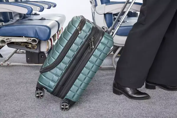 A person wheels the Delsey Paris Shadow 5.0 Carry-on with Laptop Compartment over carpet