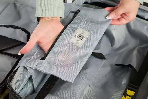 A person places their hand in the pocket of the Delsey Paris Shadow 5.0 Carry-on with Laptop Compartment