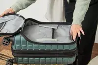 A person holds open the front pocket on the Delsey Paris Shadow 5.0 Carry-on with Laptop Compartment