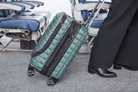A person wheels the Delsey Paris Shadow 5.0 Carry-on with Laptop Compartment over carpet