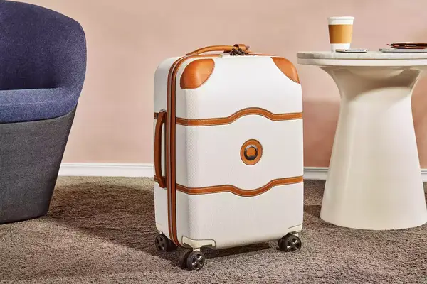 Delsey Chatelet Air 2.0 21-inch Carry-on Spinner displayed between a chair and end table